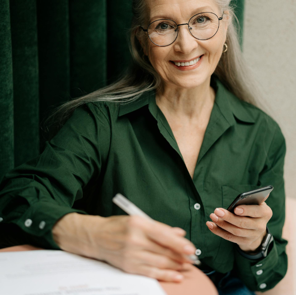 Untitled design (24) lady with grey hair, green shirt with phone in hand